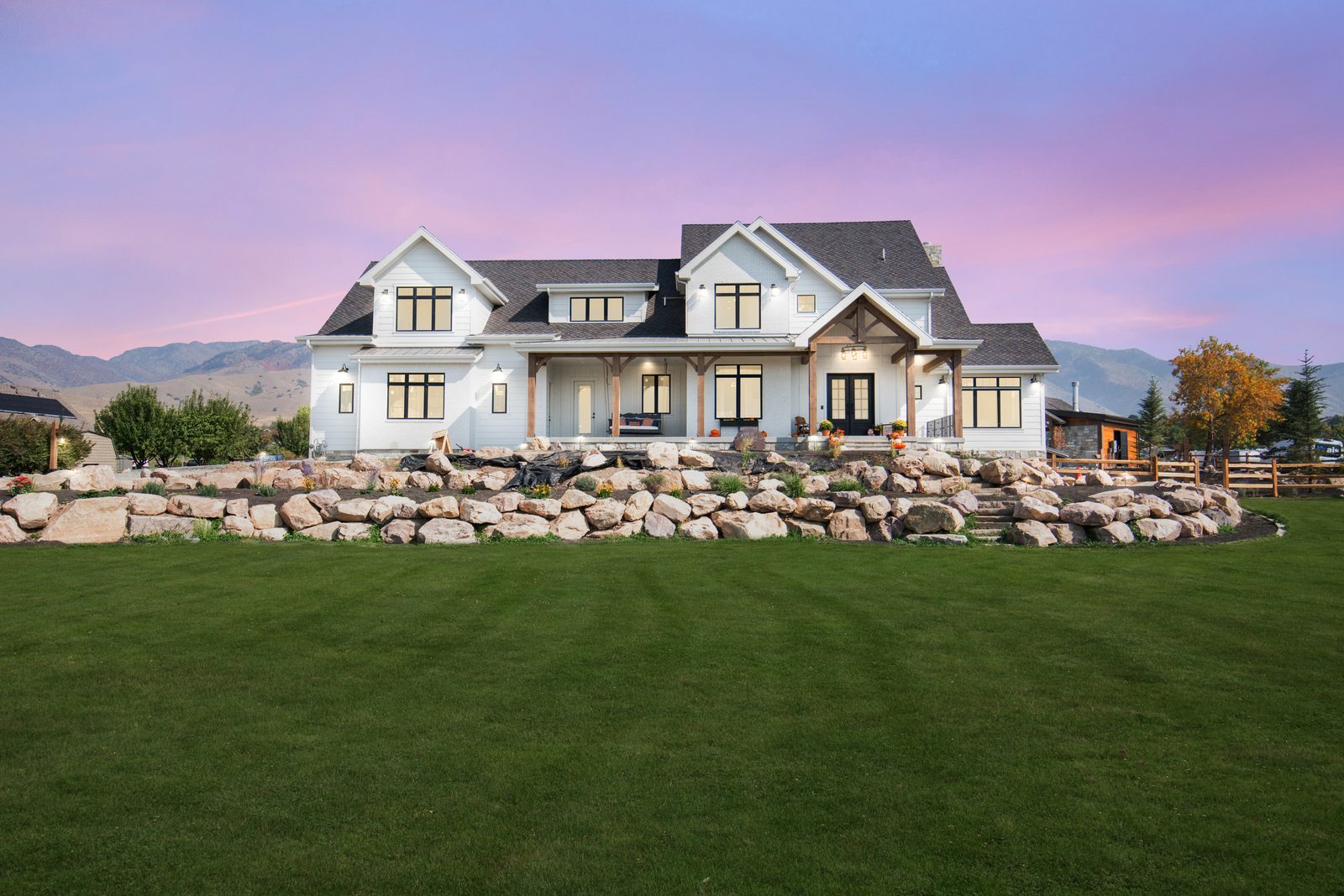 Lazy Acres, a white modern farmhouse at twilight with mountains behind, 2021 Top of Utah Parade of Homes